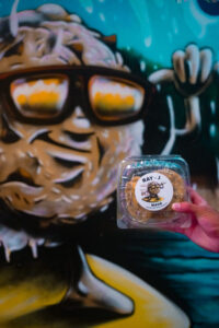 box of cookies held in front of CnC mascot mural